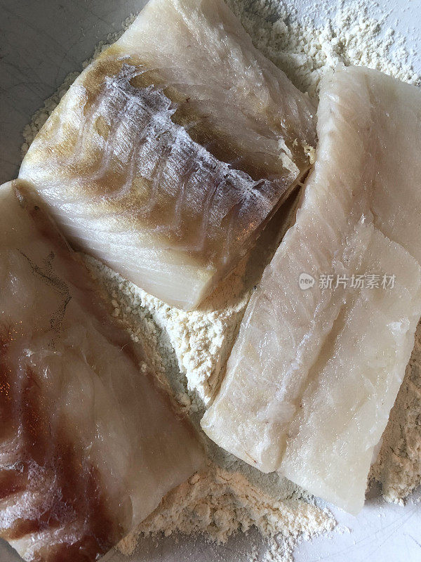 解冻后的冷冻鳕鱼片浸在面粉中，然后在热油中油炸，这是英国的炸鱼薯条/传统的英国鱼晚餐